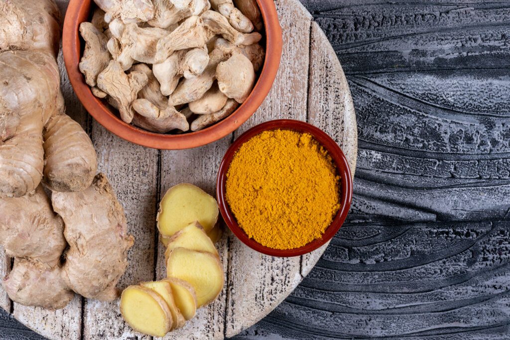 set of ginger slices and powder and ginger in bowls on a wood and dark wooden background. top view.